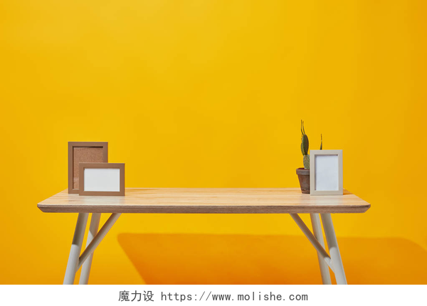 黄色背景前的木桌木桌与空相框和仙人掌在花盆在黄色
